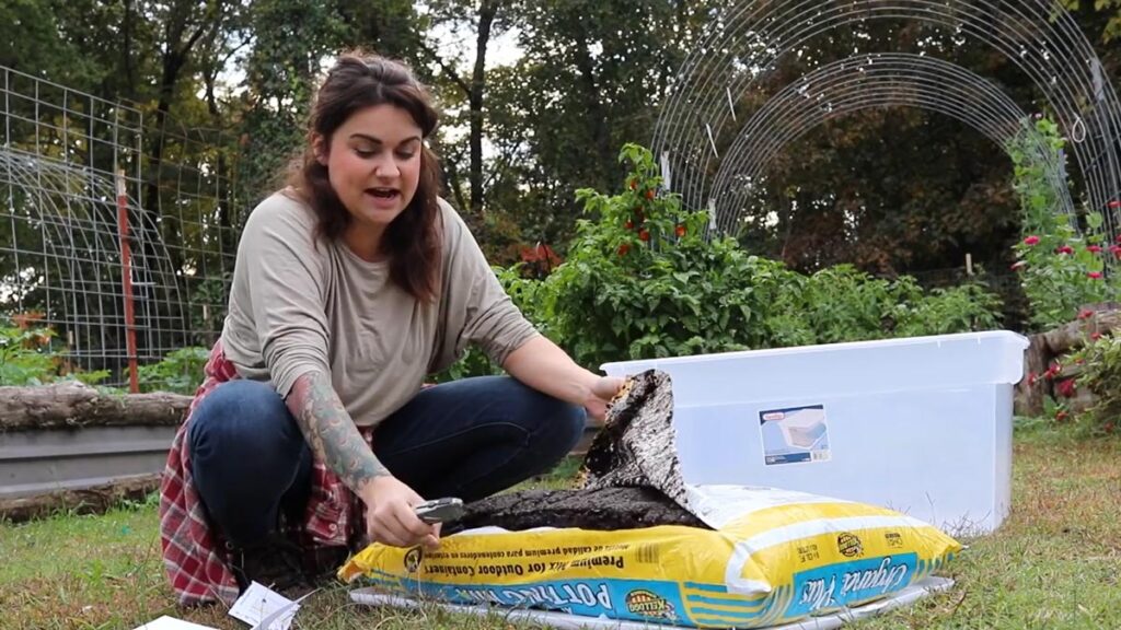 Woman cutting through a bag of potting soil.