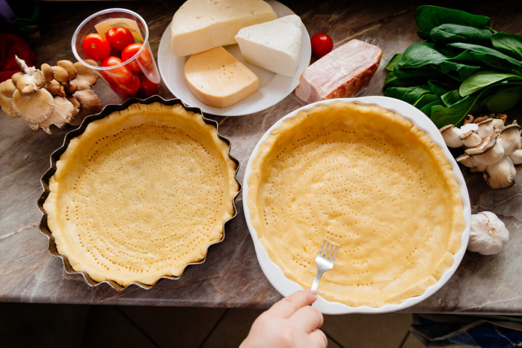 Pie crusts being pricked by a fork before baking.