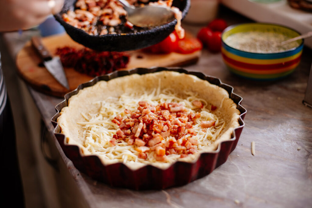 Pie crust filled with cheese and bacon for a quiche.