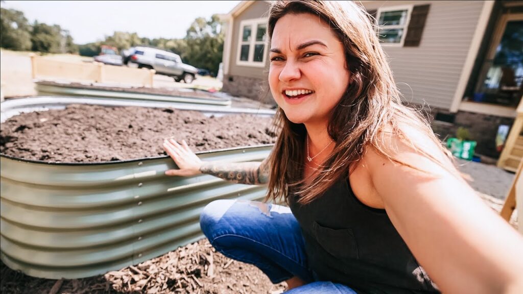 A woman crouched down by a raised garden bed.