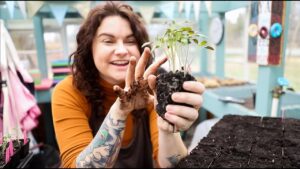 A woman holding a bundle of tomato seedlings.