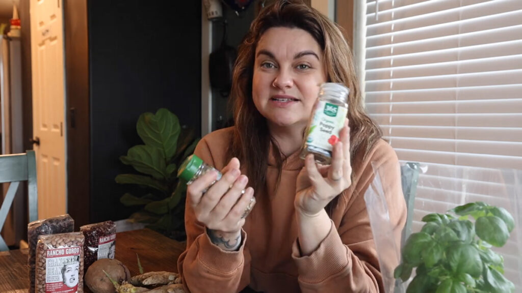 A woman holding up two jars of seeds from the grocery store.