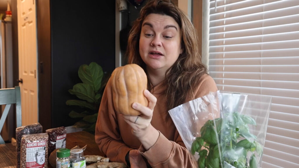 A woman holding up a winter squash.