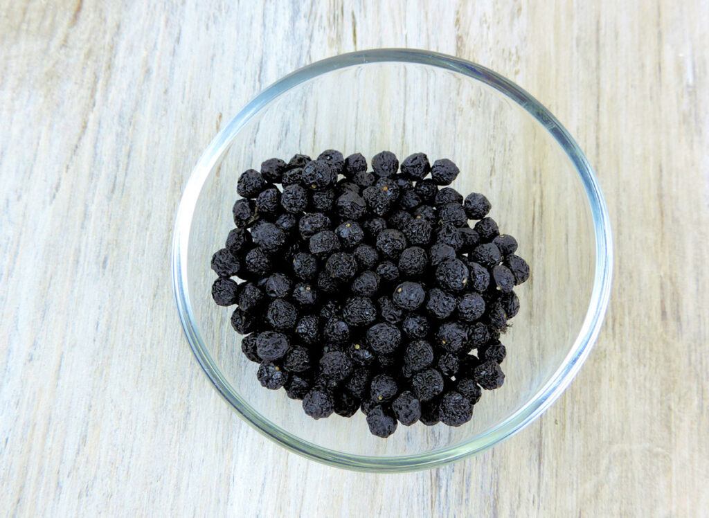 Dried elderberries in a glass bowl.