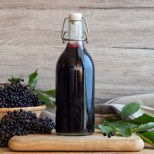 Elderberry syrup in a swing top bottle on a counter.