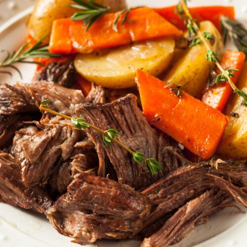 A white plate with pot roast and roasted vegetables.