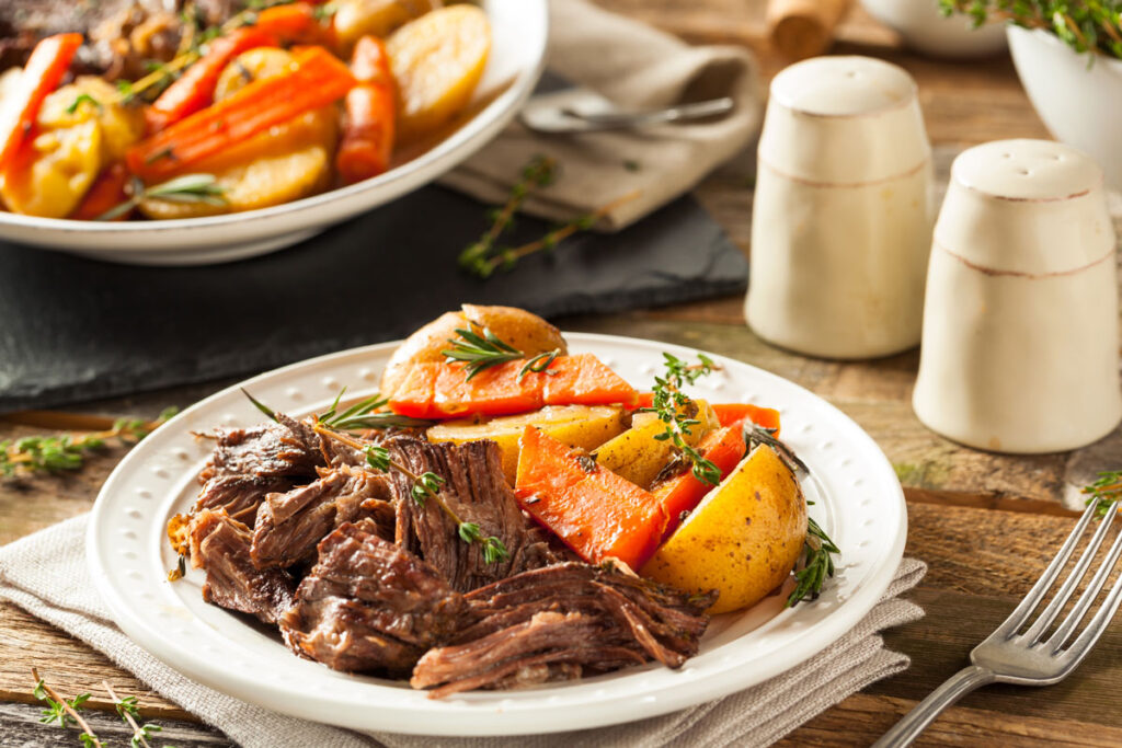 A white plate with pot roast and roasted vegetables.