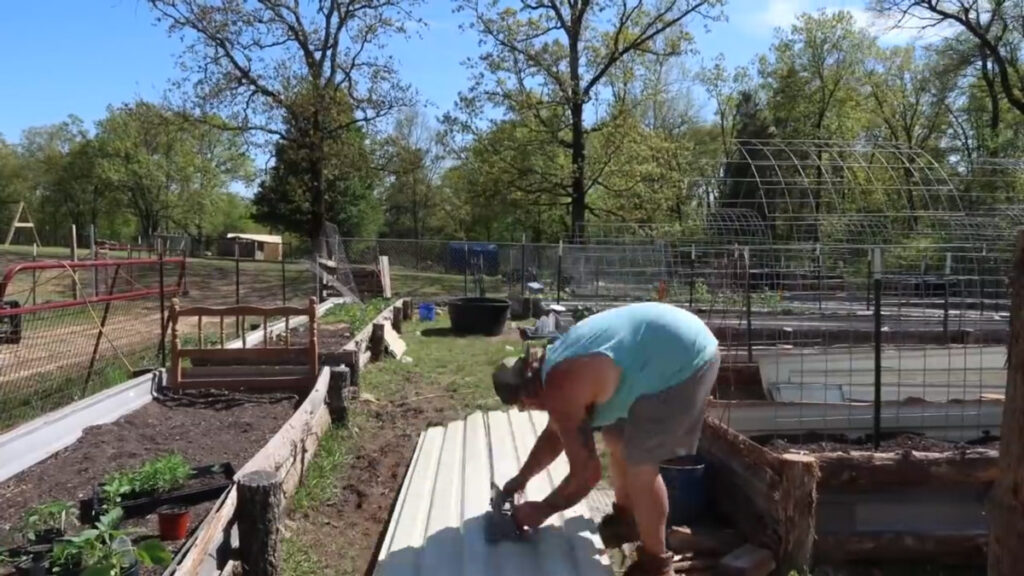 A man cutting a long piece of tin roofing with a circular saw.