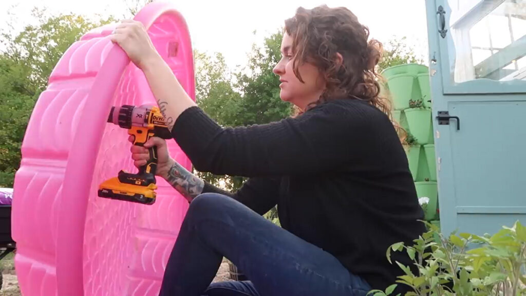 Woman drilling holes into a pink kiddie pool.