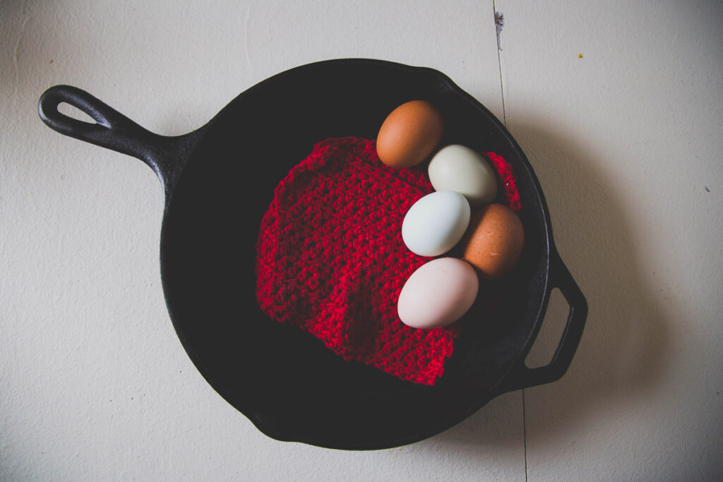 A cast iron skillet with a red cloth and five eggs inside the skillet.