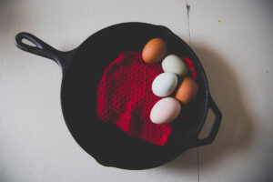 A cast iron skillet with a red cloth and five eggs inside the skillet.