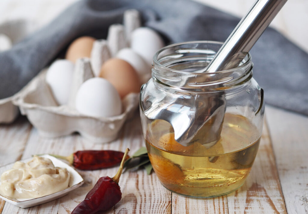 An immersion blender in a jar of eggs and oil for homemade mayo.