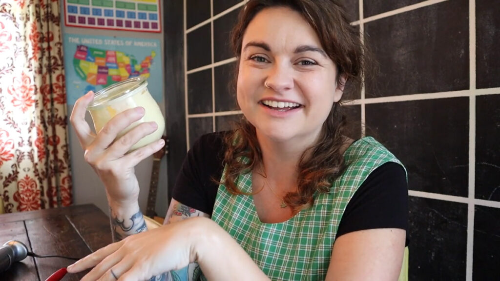 A woman holding up a jar of homemade mayonnaise.