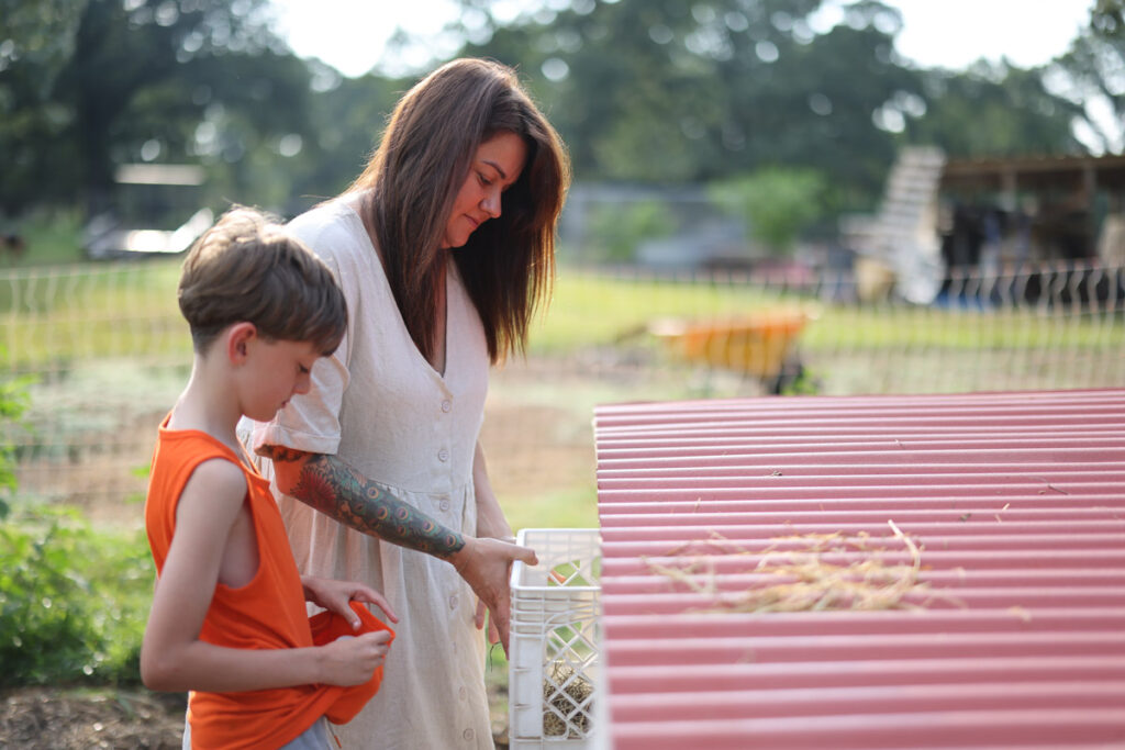 A mother and son collecting eggs from a chicken coop.