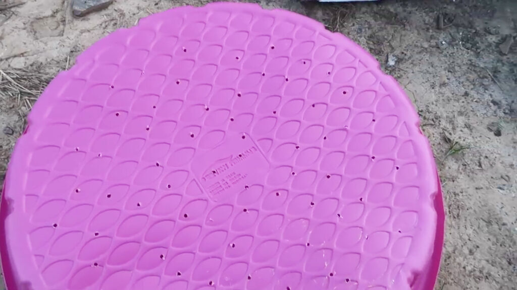 Many holes drilled into a pink kiddie pool.