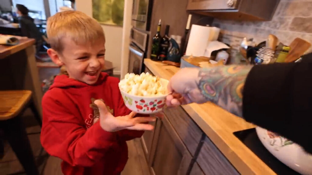A young boy being handed a bowl of popcorn.