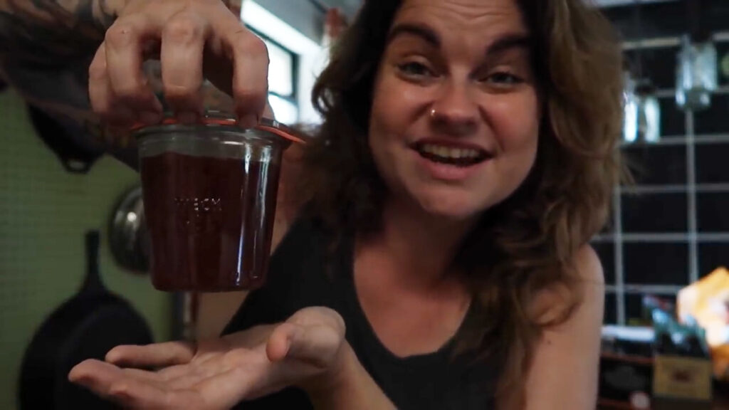 A woman testing weck jar lid seal of a jar of jam.