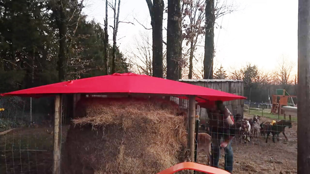 A large bale of hay under an umbrella on a structure.
