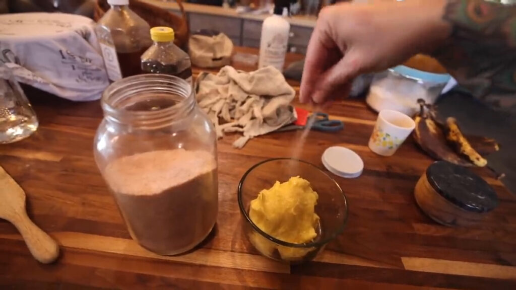 A woman's hand salting a bowl of homemade butter.