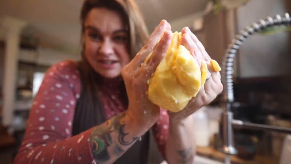 A woman squeezing out buttermilk from homemade butter.