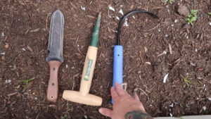 Three garden hand tools on the ground.