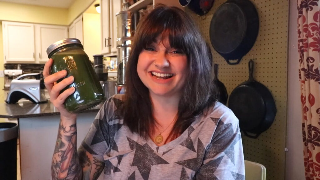 A woman holding up a quart of green juice.