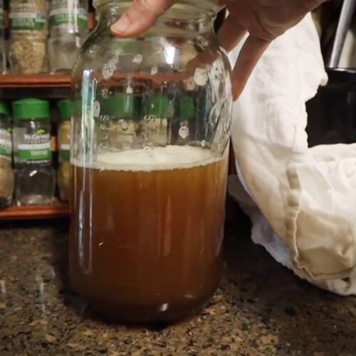 Lemon balm syrup in a half gallon mason jar.
