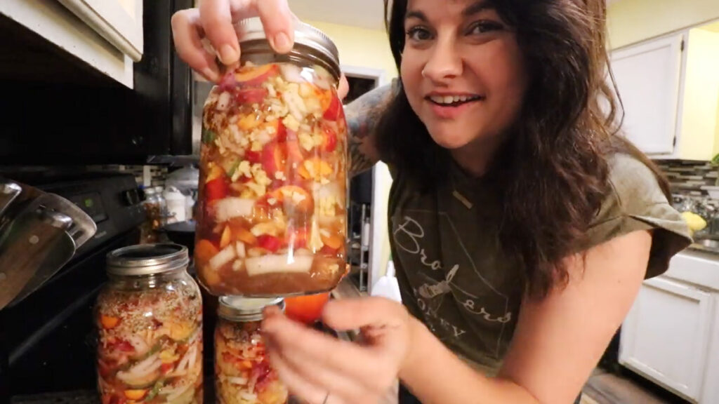 A woman holding up a jar of quick pickled veggies.
