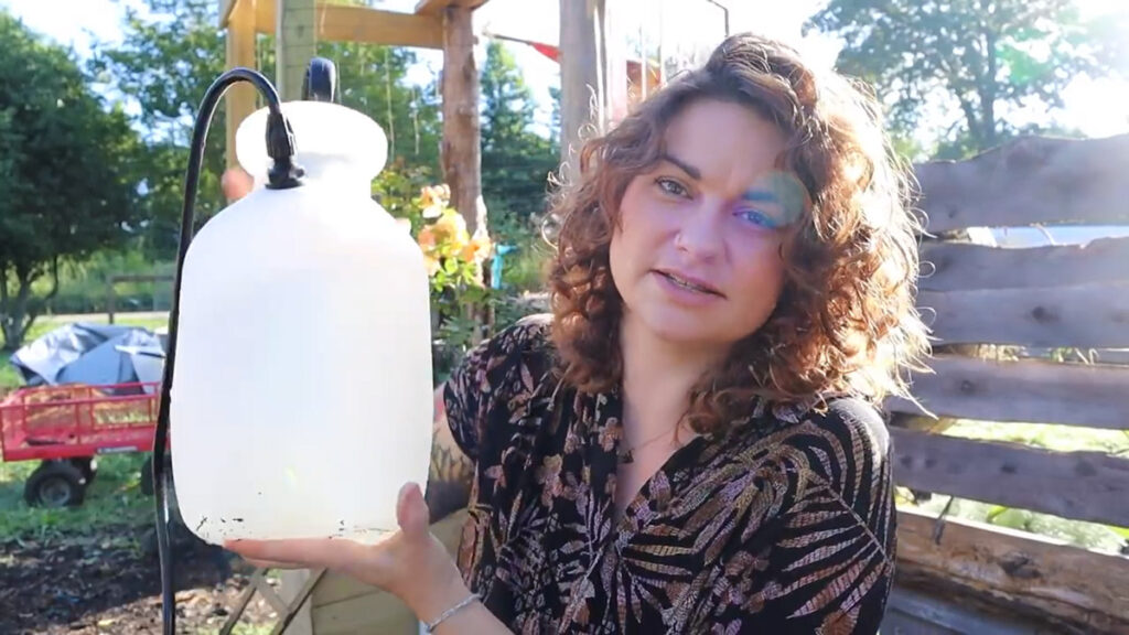 A woman holding up a 2 gallon sprayer.