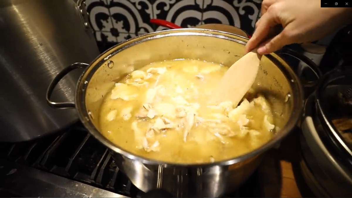 Chicken n dumpling soup in a stainless steel pot on the stove.