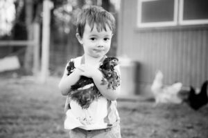 A little boy holding a chicken.