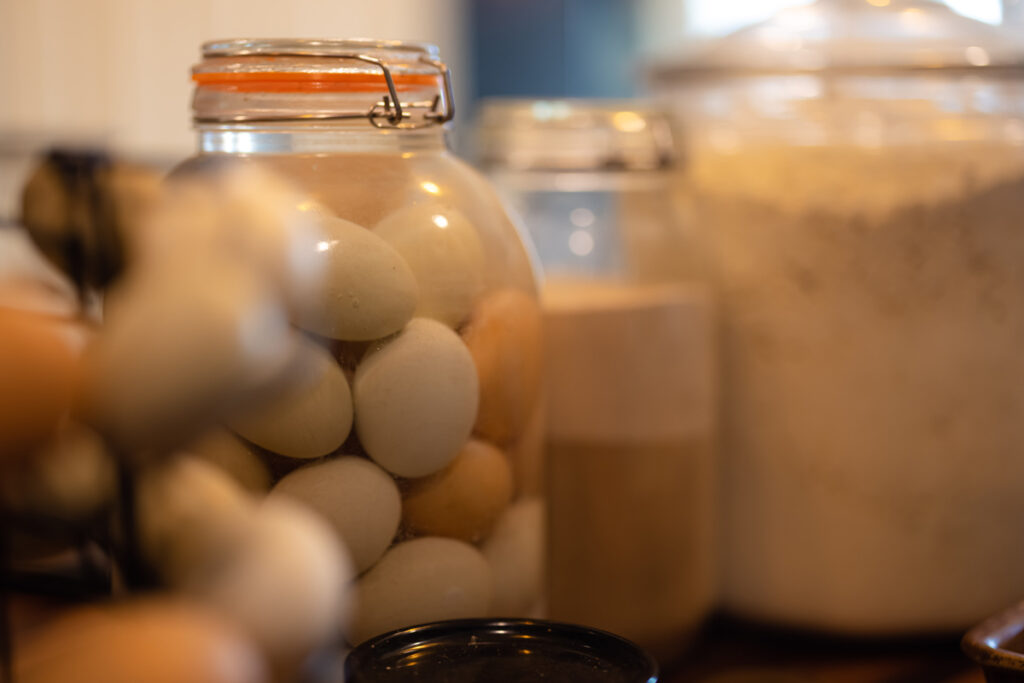 Waterglassed eggs and flour in jars on a kitchen counter.