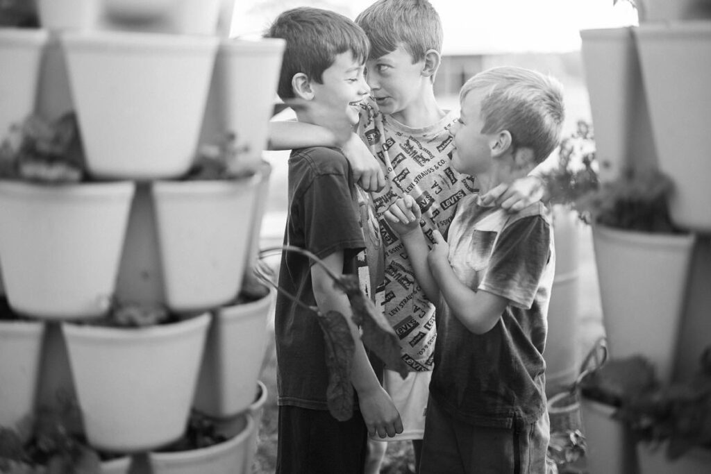 Three boys giggling in a garden.