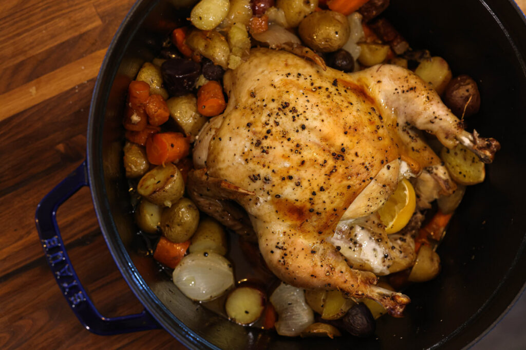 Spatchcock chicken in a cast iron roasting pan with potatoes.