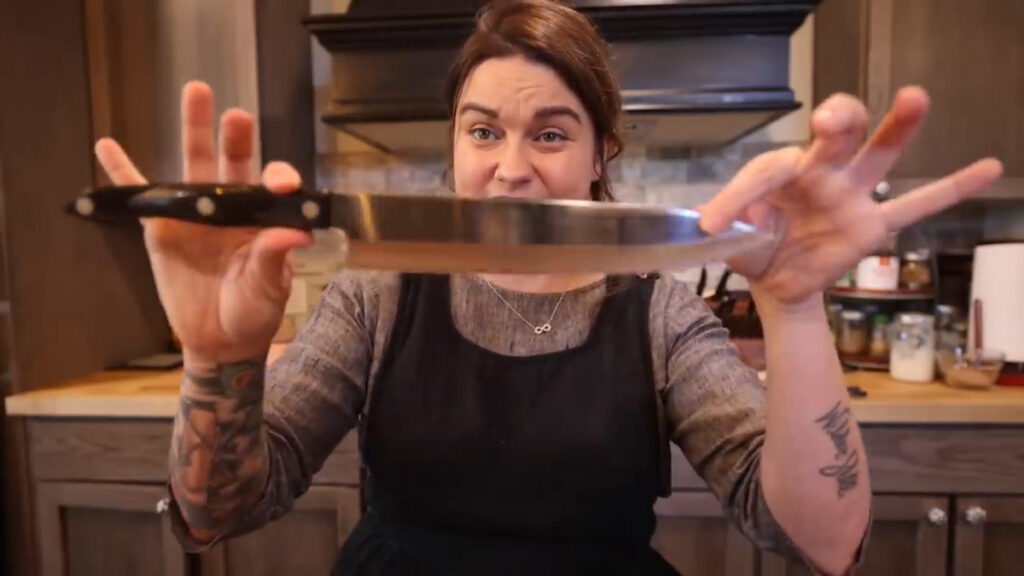 A woman holding up a chef's knife.