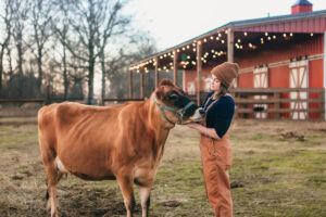 A woman giving a cow pets.