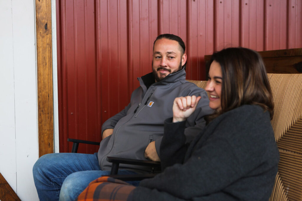 A man and woman sitting in rocking chairs next to a barn.