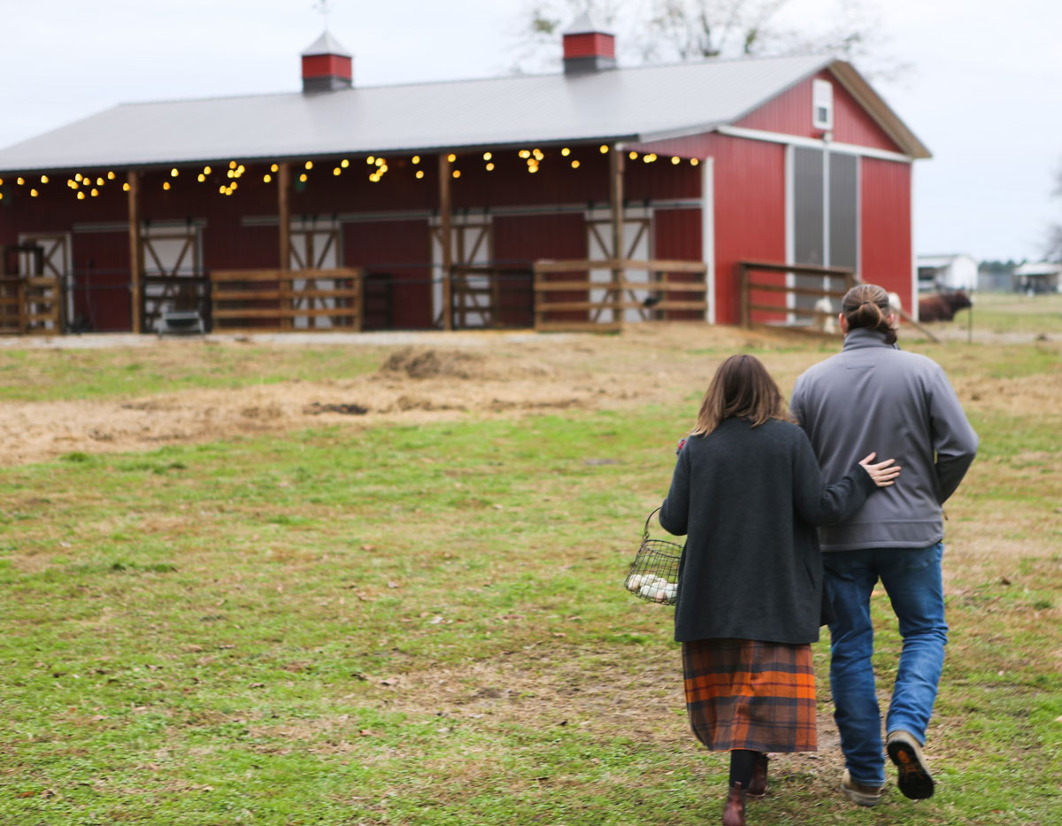 A man and woman walking toward a barn.