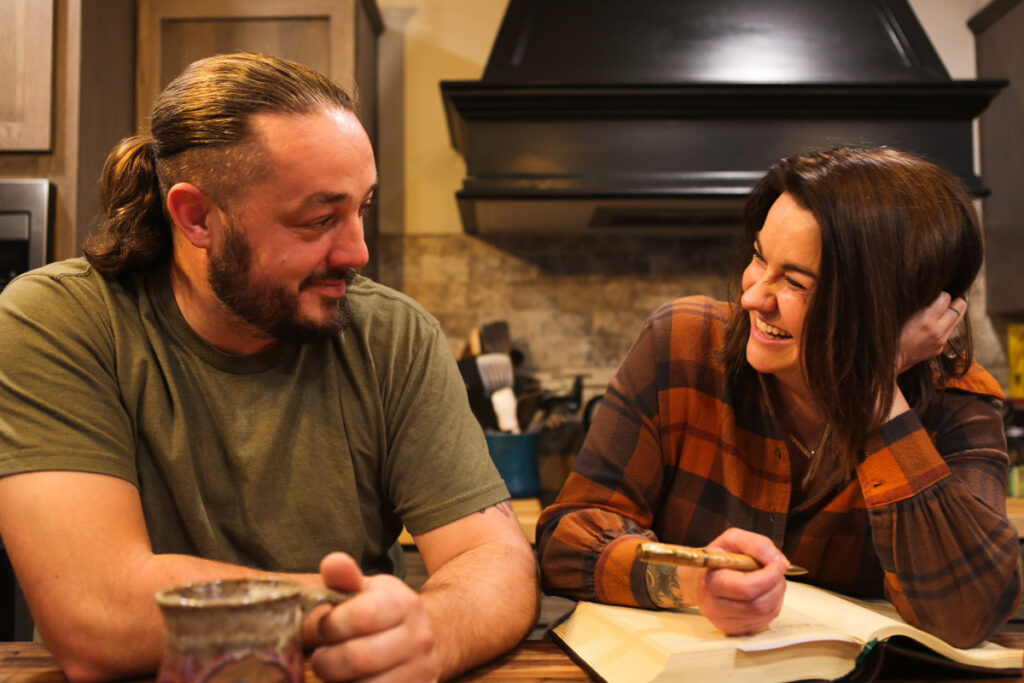 A man and woman sitting at a table in the kitchen.