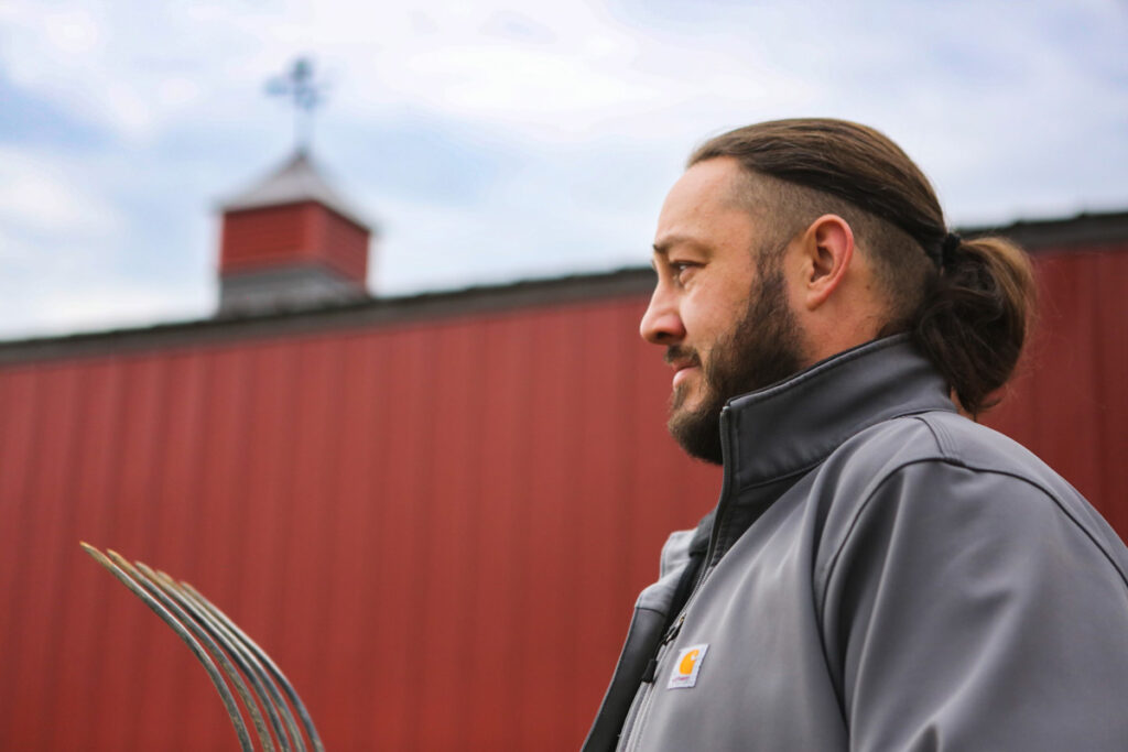 The profile of a man with a barn in the background.