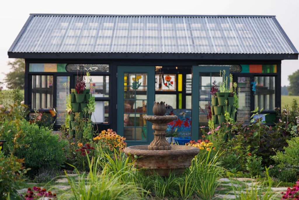 Window greenhouse surrounded by a cottage garden.