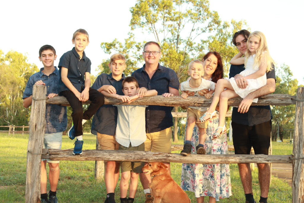 A family posing for a photo along a wooden fence.